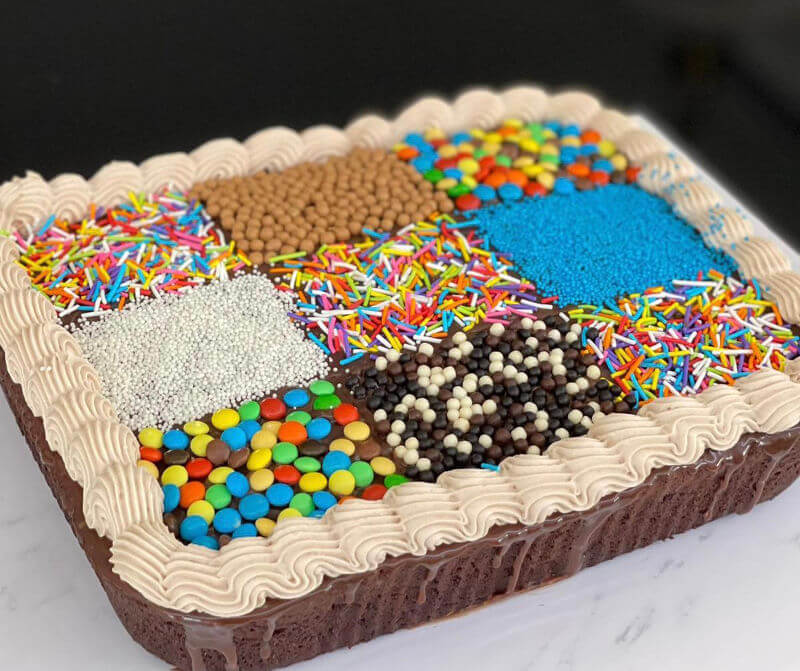 עוגת שוקולד מלבנית מחולקת לקוביות עם סוכריות צבעוניות